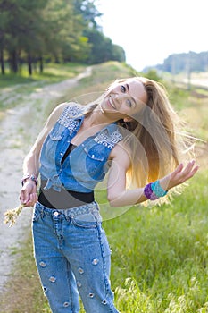 Vertical portrait of a charming slim blonde on a background of nature