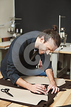 Vertical portrait of cheerful attractive caucasian mature male fashion designer with stylish hairstyle in black suit