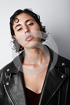 Vertical portrait of confident woman looking at the camera wears biker jacket.