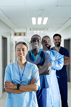 Vertical portrait of diverse group of smiling healthcare workers in line in corridor, copy space