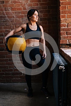 Vertical portrait of fitness young athletic woman with strong beautiful body in black sportswear posing with heavy