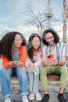 Vertical portrait of a group of best friends enjoying and smiling using their mobile phone app sharing messages. Happy
