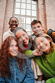 Vertical portrait of a group of friends having fun and smiling together. High school students looking at camera with