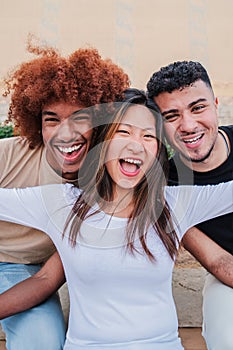 Vertical portrait of a group of multiracial teenagers laughing smiling together. Asian young woman spreading arms and