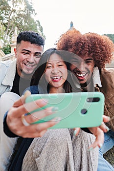 Vertical portrait of group of teenage multiracial friends having fun taking a selfie with a mobile phone. Young happy