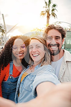 Vertical portrait. Group of young adult friends smiling taking a selfie portrait and having fun together. Group of