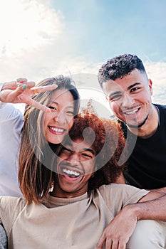 Vertical portrait of group of young multiracial friends hugging and having fun together. Three happy cool buddies