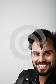 Vertical portrait of handsome biker man wearing leather jacker posing over white background. Space for text.