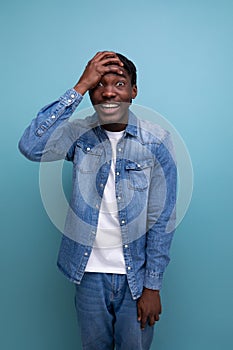 vertical portrait of handsome young stylish african man with curls in denim clothes