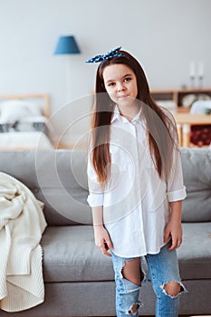 Vertical portrait of happy 10 years old kid or preteen girl relaxing at home