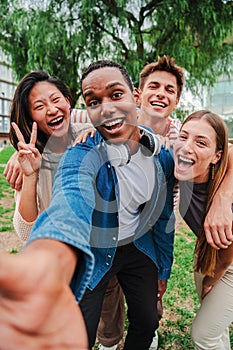 Vertical portrait of happy african american teenager laughing with his cheerful friends. Group of multiracial young