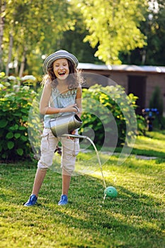 vertical portrait of happy child girl in gardener hat playing with watering can
