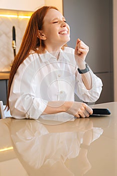 Vertical portrait of happy shocked redhead young woman saying wow using phone, have surprise or message with good news