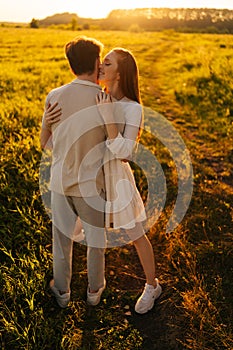 Vertical portrait of happy young woman with closed eyes and man in love embracing, kissing, stroking standing together
