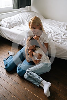 Vertical portrait of loving young mother comforting offended sad little child daughter, showing love and care