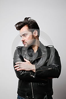Vertical portrait of modern stylish young hipster man in a leather stylish jacket posing over a white background.