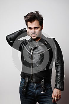 Vertical portrait of modern stylish young hipster man in a leather stylish jacket posing over a white background.