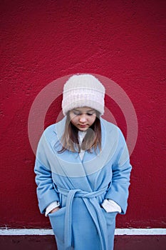 Vertical portrait of pleasent Hipster girl wearing warm casualblue coat and woolen hat on a vinous wall background. photo