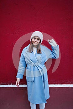 Vertical portrait of pleasent Hipster girl wearing warm casualblue coat and woolen hat on a vinous wall background. photo