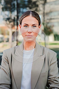 Vertical portrait of powerful business woman looking serious at camera standing at workplace. Elegant office secretary