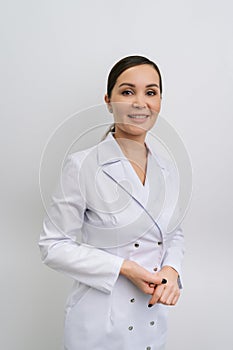 Vertical portrait of pretty female general practitioner wearing coat uniform standing on isolated white background