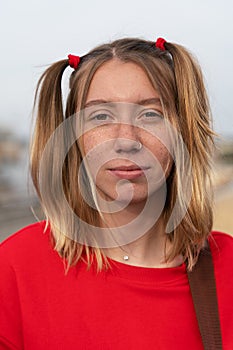 Vertical portrait of pretty young blonde woman with a soulful and intense look, freckles on her face and two funny