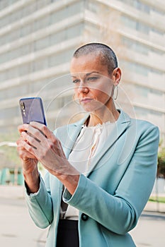 Vertical portrait of a serious business woman watching news on the cellphone. Successful businesswoman using a mobile