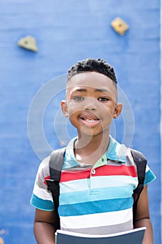 Vertical portrait of smiling african american boy in elementary school playground, copy space