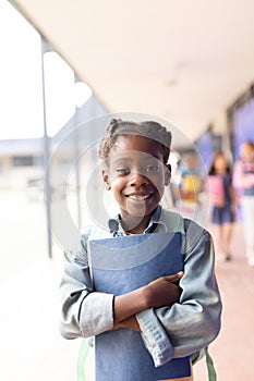 Vertical portrait of smiling african american girl in elementary school corridor, with copy space