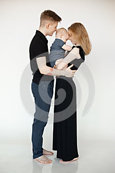 Vertical portrait of smiling calm barefoot woman, man, baby, hugging and spending time together. Reunion family, side