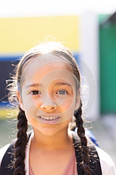 Vertical portrait of smiling cauasian elementary schoolgirl in school playground, copy space photo