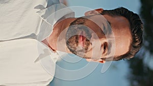 Vertical portrait smiling hispanic man taking off sunglasses on sunny viewpoint