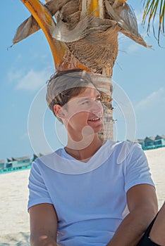 Vertical portrait of smiling man relaxing on the beach at the tropical island luxury resort
