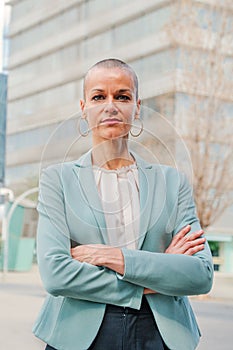 Vertical portrait of successful business woman standing arms crossed at workplace looking at camera. Corporate female