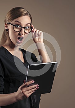 Vertical Portrait of surprised Young girl wearing eyeglasses and holding digital tablet