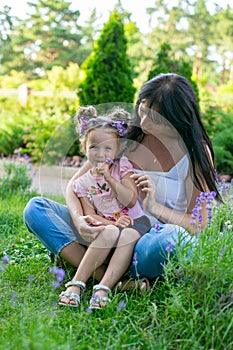 Vertical portrait of a thirty five year old woman with three year old daughter against the background of a summer park