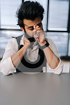 Vertical portrait of tired exhausted Indian businessman massaging nose bridge, taking off glasses, feeling eyestrain