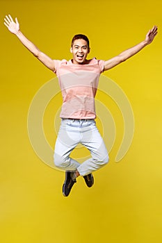 Vertical portrait of wild and free, enthusiastic asian male student finally passed all university exams, jumping up and