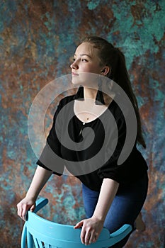 Vertical portrait of a young blonde against the background of a beautiful wall