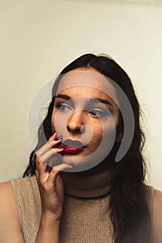 Vertical portrait of a young caucasian woman with dark red lipstick and nails