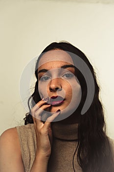 Vertical portrait of a young caucasian woman with dark red lipstick and nails