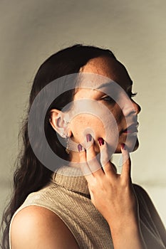 Vertical portrait of a young caucasian woman with dark red lipstick and nails