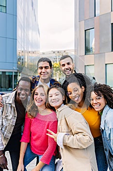 Vertical portrait of young group of diverse people smiling at camera outdoors.