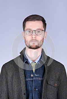 Vertical portrait of a young man with a beard and glasses in sty