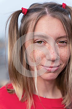 Vertical portrait of young smiling blonde woman with a soulful and playful look, freckles on her face and two funny