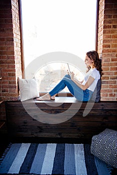 Vertical profile side view of her she nice attractive lovely focused wavy-haired girl sitting on window sill reading e