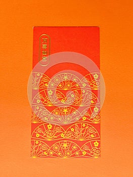 A vertical red envelope with the word \'All the best\' on it and a fan decorating the bottom on orange background.