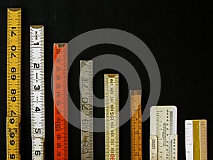 Vertical row of old rulers suggests a graph of decreasing return photo