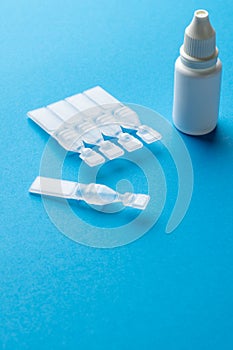 Vertical of saline solution caplets and dropper bottle on blue background with copy space