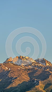 Vertical Scenic view of a mountain peak with rugged slopes and dusted with snow